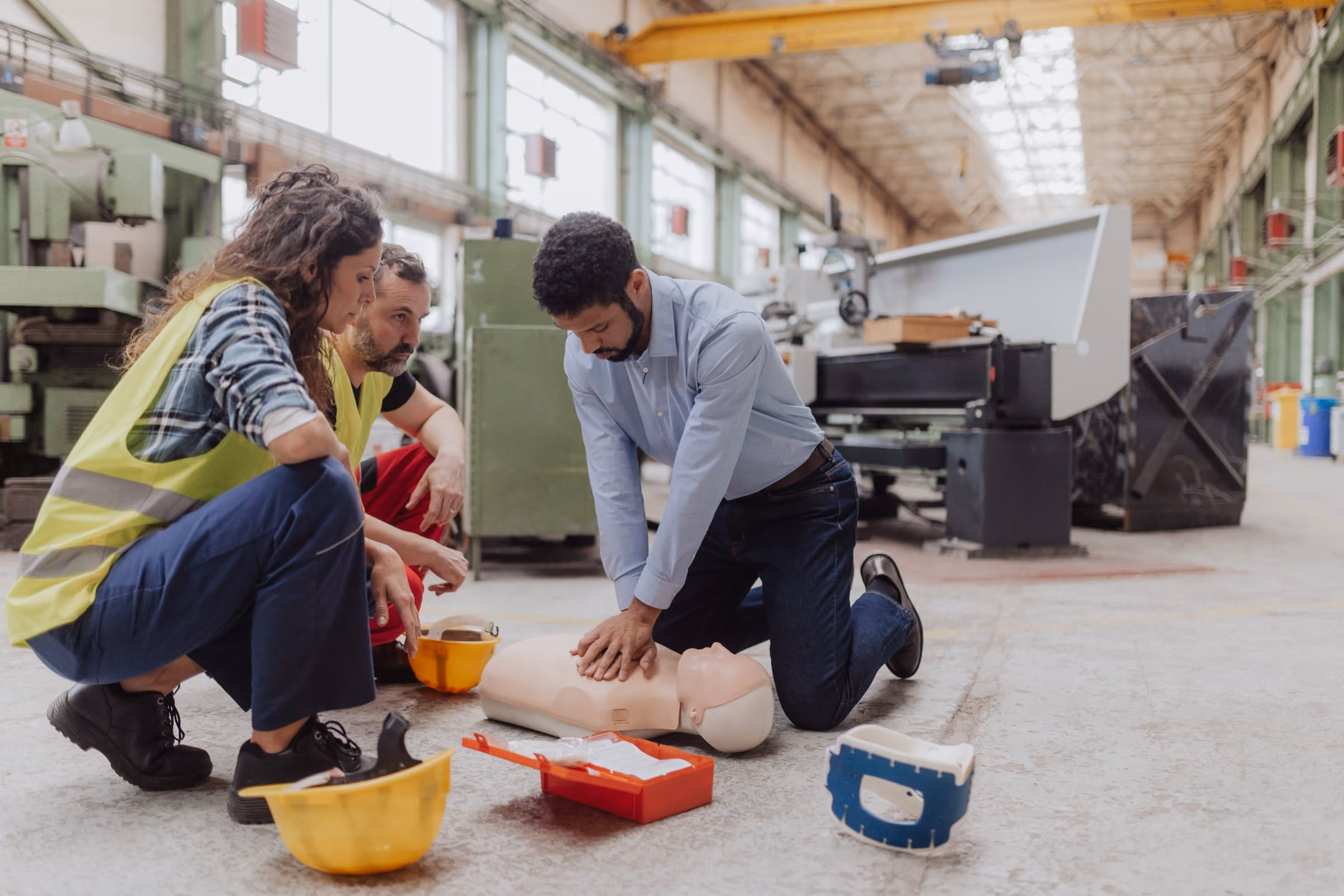 Des employés s'exercent à la réanimation sur un mannequin dans un atelier, pendant une formation en entreprise
