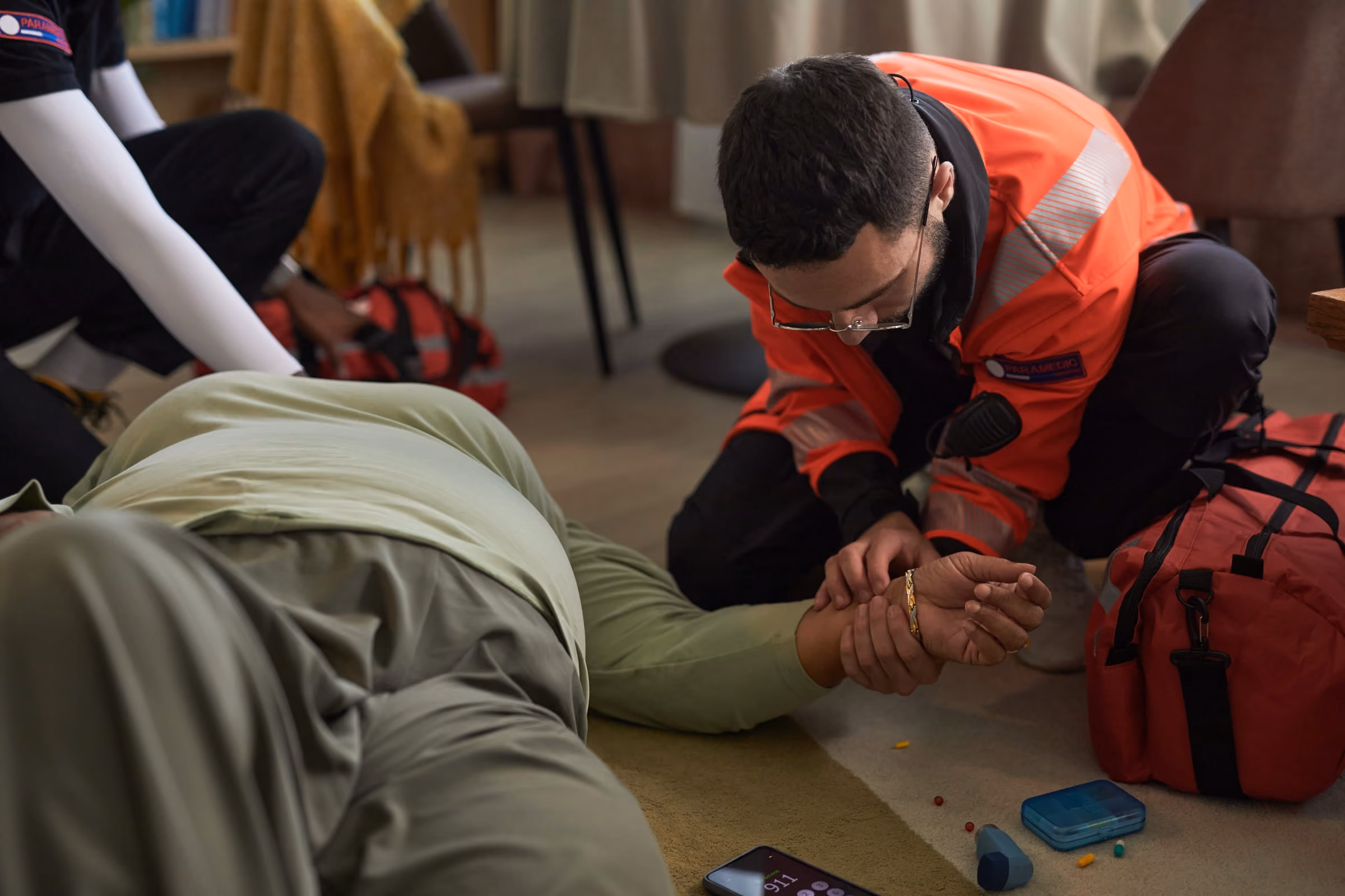 Un ambulancier en veste orange prend le pouls d'une personne allongée