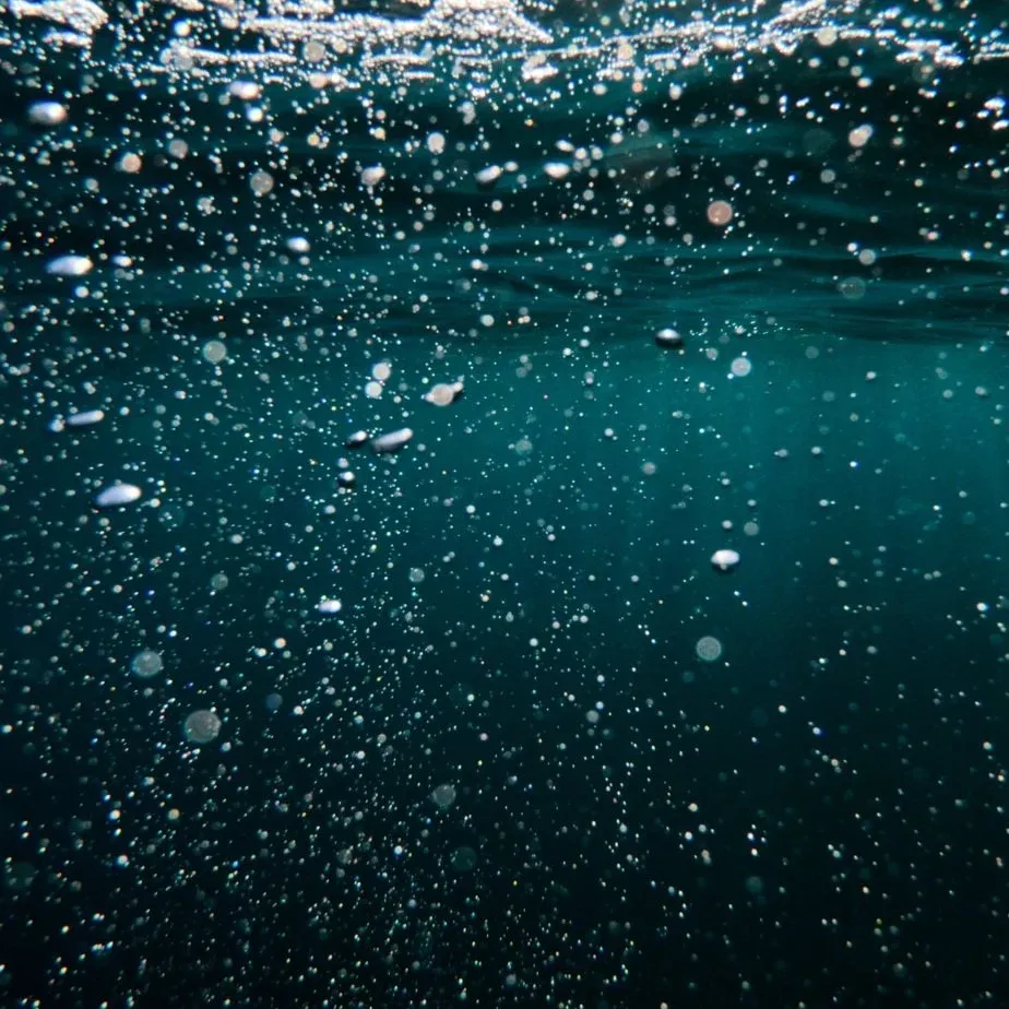 Bulles d'air remontant dans une eau turquoise